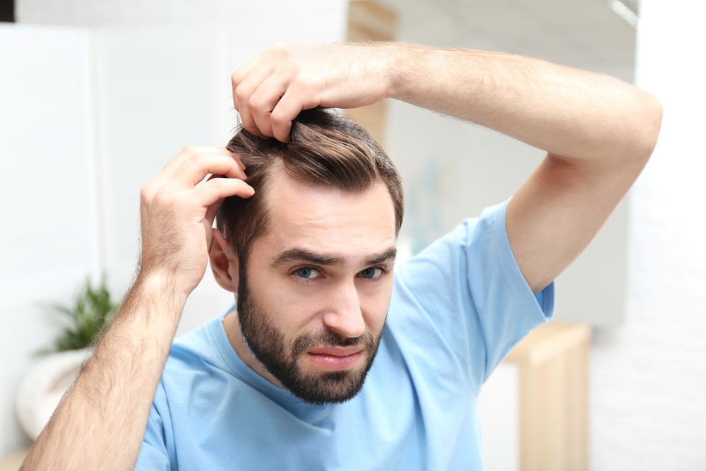 Man is unhappy with his receding hairline as he looks into a mirror. Man is unhappy with his receding hairline as he looks into a mirror.